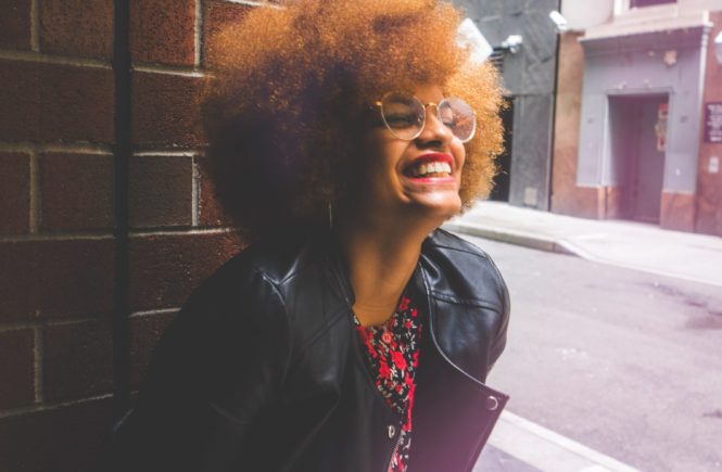 woman with natural hair with winter black jacket smiling