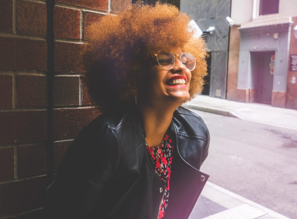 woman with natural hair with winter black jacket smiling